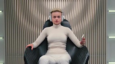 Kafkasyalı fütürizm kadın kablosuz kulaklık takıyor. Cep telefonu uygulaması kullanıyor. Müzik servisi, akıllı telefondan şarkı seçiyor.