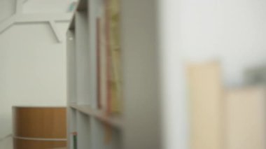 Afrikalı Amerikalı erkek öğrenci kütüphanede elinde kitaplarla geziyor. Kitaplık bakıyor. Üniversite öğrenimi görüyor, hobi araştırmaları okuyor.