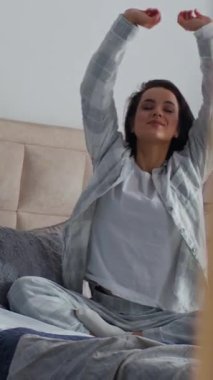 Aynadan yansıyan beyaz kadın yatakta uyanıyor, ellerini uzatıyor, sabah erkenden uyanıyor, mutlu bir bayan, yatak odasında rahat, rahat, daire zindeliği ile güne başlıyor.