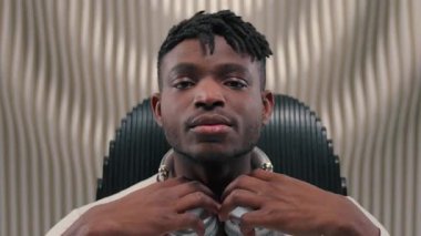 Afro-Amerikalı erkek adam kulaklık takıyor, müzik dinliyor, gözleri kapalı sakin sakin sakin dinleniyor, fütürizm teknolojisinin tadını çıkarmak için fütüristik uzay stüdyosunda arkasına yaslanıyor.