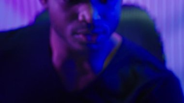 Karanlık neon fütüristik odada cep telefonuyla kazanan neşeli Afrikalı Amerikalı adam sevinçli erkek arkadaşla bağırmaktan memnun. Akıllı telefon kutlamasıyla kazanan kişi mesaj oyunu zaferini çevrimiçi bahis fütürizmi sunuyor.