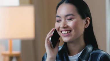 Mutlu Koreli Asyalı kadın cep telefonuna cevap veriyor. Gülümsüyor, güler yüzlü Japon bayan sohbet ediyor. Uzaktan iletişim kuruyor.