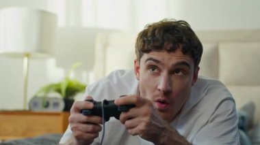 Heyecanlı Kafkasyalı adam evde yatıp video oyunu oynuyor. Oyun kumandası, oyun konsolu yarışması, eğlence, eğlence, eğlence, sanal eğlence, elektronik kontrol siber yatak odası.