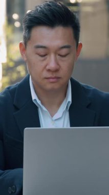 Odaklanmış Asyalı iş adamı bilgisayarla sohbet ediyor. Bilgisayar Koreli iş adamı kullanıyor. Modern siber uzay teknolojisi internet üzerinde çalışıyor.