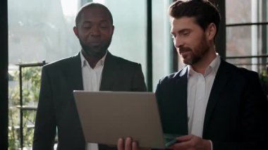 Çeşitli iş adamları iş arkadaşları dizüstü bilgisayarlar arayan iş adamları tasasız bir şekilde online sonuçları tartışan iki çok ırklı yönetici ofiste birlikte bilgisayar kullanarak neşeli takım çalışması yapıyorlar.