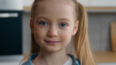 Yakın portre beyaz mutlu küçük kız sakin güzel gülümseme ev mutfağındaki kamera aile velayeti sevimli kız kapalı alanda çocuk gülümsemesi pozitif yüz ifadesi