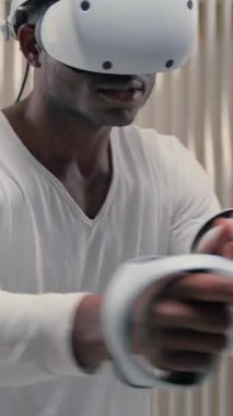 Sanal gerçeklikle oynayan Afrikalı Amerikalı bir adam kontrolörlerle silah çekiyormuş gibi yapıyor. Erkek adam internet teknolojisi fütürizm siber oyun metatik hobisinde VR kaskı oynuyor.