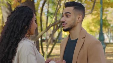 İspanyol mutlu çift, sonbahar parkında birbirlerine sarılıp el ele tutuşuyorlar. Sonbaharda sokaklarda el ele tutuşuyorlar. Evli çiftler güler yüzlü bir şekilde sarılıyorlar.