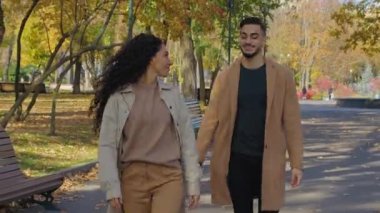 İspanyol mutlu çift, güz parkında el ele yürüyorlar. Gülümsüyorlar. Dönen kadın etrafında dönüyorlar. Sarılıyorlar.