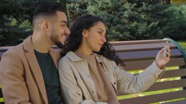 Neşeli İspanyol çiftin görüntülü konuşması cep telefonu uygulaması, sanal internet sohbeti, güler yüzlü sosyal medya vlog 'u, güler yüzlü güler yüzlü sonbahar parkındaki adam ve kadın gülüşü, mutlu bir şekilde selamlaşır.