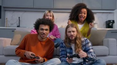 Çok ırklı arkadaşlar, video oyunu oynayan erkekler ve kadınlar gülüyorlar. Kafkasyalı kadınlar, Afro-Amerikalı erkekler, eğlence, eğlence, eğlence, oyun, oyun, bağımlısı.