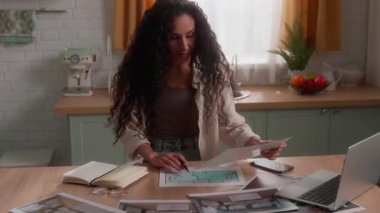 Düşünceli İspanyol iş kadını dizüstü bilgisayarda çalışıyor. İç dizayn fotoğraflarına bakıyor. Mutfak fotoğraflarına odaklanmış iş kadını.