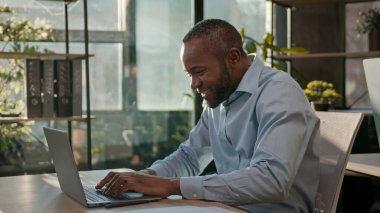 Afrikalı 40 'lı yılların iş adamı dizüstü bilgisayarı internet hizmeti siber uzay yetişkin iş adamı ofiste çalışıyor olgun erkek yönetici yönetici yönetici geliştiricisi bilgisayar veri programlama ile gülümsüyor