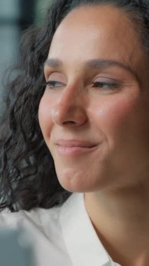 Yakın plan, tatmin olmuş İspanyol iş kadını ofiste sakin sakin bir müzik dinliyor bilgisayarlı Arap iş kadını iş yerinde gülümseyen müzik parçalarını dinliyor.