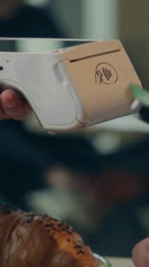 Kafe işletmecisiyle cep telefonuyla ödeme yapan tanınmamış bir ziyaretçi müşteriyi kapatın. Bilinmeyen iş adamı. Erkek, yemek siparişi veren, kahve ısmarlayan, restoranda NFC terminali teknolojisi sipariş eden.