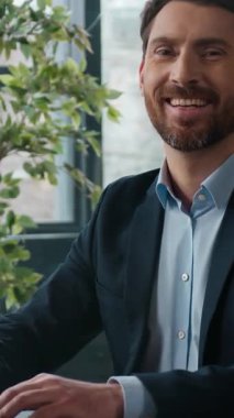 Odaklanmış Kafkas işadamı ofiste dizüstü bilgisayar yazarken kameraya bakıyor mutlu işçi işçi profesyonel girişimci erkek yönetici işveren çevrimiçi iş adamı portresi