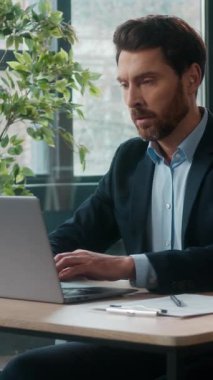 Düşünceli şaşkın Kafkasyalı ofis işadamı bilgi analizi yaparken bilgisayar uzmanı erkek girişimci yönetici kullanarak notlar yazıyor iş adamı adam.