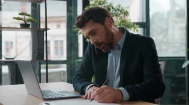 Kafkasyalı iş adamı, ofisteki hayal kırıklığına uğramış erkek yöneticinin bilgisayarında cep telefonu daktilo dizüstü bilgisayarını tartışıyor hoşnutsuz erkek danışman girişimci içeride müşteri kontrolü yapıyor.