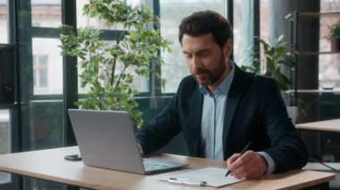 Ofiste dizüstü bilgisayarda yazı yazan Kafkasyalı başarılı bir iş adamı profesyonel yetişkin muhasebeci, erkek muhasebeci, yönetici ve bilgisayar işyeri verilerini girmekle meşgul.