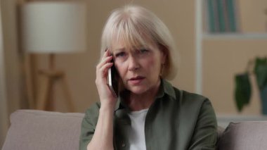 Negatif üzgün, Kafkasyalı bir kadının evde cep telefonu sorunları hakkında konuşması, üzgün hissetmesi, yaşlı ve yaşlı bir kadının akıllı telefonuyla konuşması, kötü haber üzüntüsü.