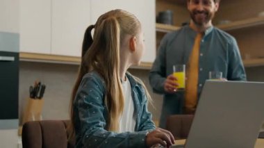 Kafkas aile babası, küçük kız çocuğuna iki bardak portakal suyu getiriyor. Laptop öğreniyor, içiyor. Ebeveynlerin sağlıklı beslenme vitaminlerinin keyfini çıkarıyor.