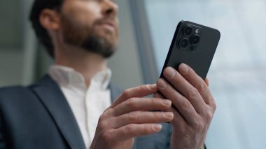 Sakin Kafkas 'lı 40' lı yılların işadamı ofiste cep telefonu kullanıyor. Pencereden dışarı bakıyor. Erkek girişimci, dalgın iş adamı internette akıllı telefonlardan sohbet ediyor.