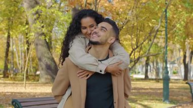 Sonbahar parkındaki mutlu İspanyol çift, gülen kadını kucaklayan, gülen, gülen, gülen, güz mevsiminin tadını çıkaran, rüzgârlı, yaprak yapraklı, altın yapraklı, neşeli Arap aile buluşması yapan evli bir adamla evli.