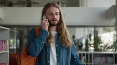 Sinirli, sinirli, Kafkasyalı öğrenci cep telefonuyla konuşuyor. Sinirli erkek, akıllı telefonla tartışıyor. Üniversitedeki yanlış anlaşılma konuşmalarında tartışma tartışıyor.