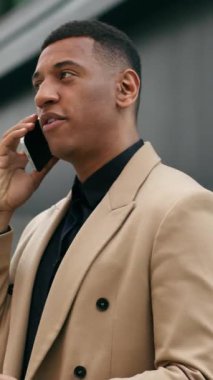 Şehir merkezinde cep telefonuyla konuşan profesyonel Afro-Amerikalı iş adamı. Yürüyen satıcı yatırımcı, akıllı telefon görüşmesi, şehirli iş adamı görüşmesi, telefon görüşmesi.