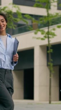 Mutlu gülümseyen Afro-Amerikan iş kadını dans ederek şehirde yürümeyi kutluyor dizüstü bilgisayarlı kadın iş kadını neşeli, aktif, şehir dışı kariyer hareketi yapıyor.