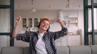 Kafkasyalı genç kızıl saçlı kadın müzik kulaklıkları dinliyordu. Evdeki koltukta dans ediyordu. Mutlu, rahat, ev hanımı, dinlenen kulaklıkların keyfini çıkarıyordu.