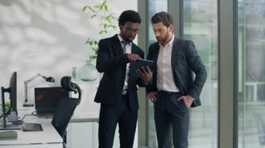 Modern dijital tablet kullanan iki farklı iş adamı, internet üzerinden iş arkadaşlarıyla internet üzerinden iş geliştirme ortakları hakkında konuşuyor.