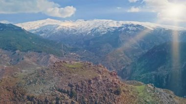 Güney İspanya 'daki görkemli Sierra Nevada sıradağları yeşil vadilerin ve kar kaplı tepelerin üzerinde parlak güneş ışığı ve nefes kesici doğal manzaralar mavi gökyüzü manzaralı yolculuğun altında huzur dolu vahşi doğa.