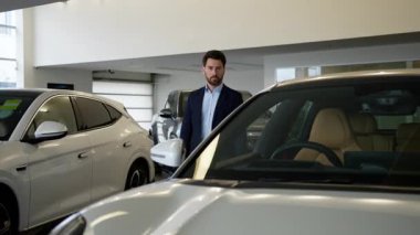 Zengin Kafkasyalı işadamı, galeride modern elektrikli arabayı seçiyor. İş adamı, galeri sahibi, lüks otomobil sahibi müşterisi. Hayalindeki aracı satın alıyor.