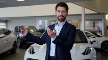 Kafkasyalı iş adamı müşteri araba bayiliğini davet ediyor. Gülümseyen iş adamı el hareketi, gülümseyen iş adamı, oto kuaför, araba kiralama servisi, otomobil satış danışmanı satış danışmanı satış teklifi.