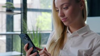 Kafkasyalı iş kadını cep telefonuyla sohbet ediyor akıllı telefonlu iş kadını gülümsüyor sosyal medyada kayan kadın internetteki internet uygulaması konuşmasında ofiste mutlu bir şekilde gülümsüyor.