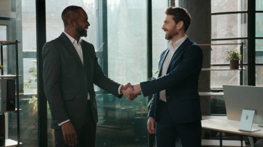 İki erkek iş adamı çok ırklı iş adamları ofis çalışmasında el sıkışıyorlar ortaklık çok uluslu işbirliği meslektaşları beyaz Afrikalı Afrikalı Amerikalı ortakların ticaretini yapıyor.