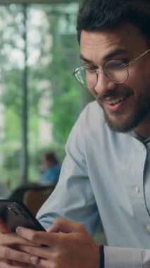 Hintli gülümseyen işadamı cep telefonu uygulaması kullanarak kahve evi Arap iş adamı erkek adam kafedeki internet akıllı telefonuna göz gezdirirken kamera karşısında durakladı.