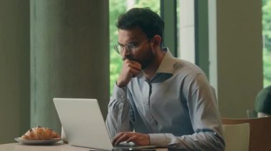 Etnik Hintli iş adamı dizüstü bilgisayar işini düşünürken, Arap iş adamının, erkek girişimcinin, düşünceli girişimci olduğunu düşünmesi ve kafeterya restoranındaki masada bir fikir edinmesi fikrini ortaya attı.