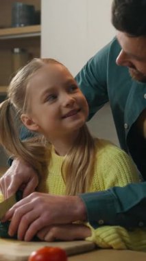 Gülümseyen aile yemekleri neşe dolu sebze salatası evde sağlıklı sebze salatası, evlat edinilmiş kız çocuk baba ile birlikte salatalıkları dilimlemeyi öğreniyor ve sevimli kızına yardım ediyor.