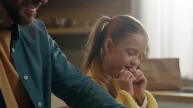 Kafkasyalı mutlu bir aile 10 'lu mutfakta kahvaltı yapıyor. Kızları kıtır kıtır ekmek yiyor. Konuşan babalara gülümsüyor.