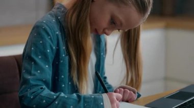 Beyaz kız, evde karantina ailesinden online ders çalışıyor. Mutfakta uzaktan öğretmenle konuşup notlar yazıyor. Öğrenci kız öğrenci laptopla ev ödevi hazırlıyor. Sınavlara hazırlanıyor.