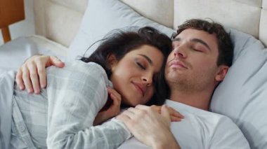 Beyaz erkek, kadın, beyaz erkek, yatak odasında uzanıyor, sarılıyor, sevgi dolu gözlere sarılıyor, uyukluyor, dinleniyor, şekerleme yapıyor, tatlı balayı sevgilisinin sevgilisine şefkatle sarılıyor.