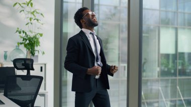 Ofiste mutlu bir iş adamı olan Afrikalı Amerikalı işadamı erkek işadamı zafer kazanma tepkisi veren bir iş adamı dans ederek başarılı bir iş fırsatı yakalayan başarılı bir atlayış yapan başarılı bir başlangıç yapan