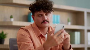 Kafkasyalı iş adamı cep telefonuyla sohbet ediyor akıllı telefon uygulaması ciddi işadamı erkek çalışan yönetici sosyal medyada sohbet ediyor web uygulaması uzmanı cep telefonunu ofiste kaydırıyor.