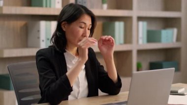 Hasta, yorgun, Asyalı iş kadını dizüstü bilgisayar başında çalışan Çinli iş kadını Japon, orta yaşlı, yetişkin, migren ağrısı çeken bir iş kadını.