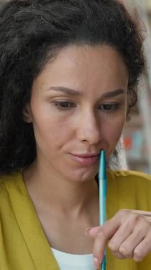 Latin Arap kökenli düşünceli bir kadın kütüphanede iç görü kalemi düşünüyor gülümseyen kız öğrenci yazar gazeteci ev ödevi entellektüel hayal gücü eğitimine ilham veriyor.