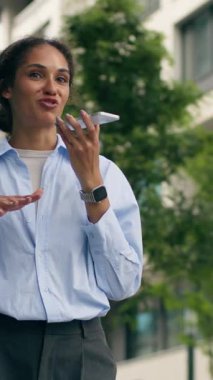 Gülümseyen Afrikalı Amerikalı iş kadını şehir dışında akıllı telefonlardan konuşuyor. Kadın öğrenci iş kadını CEO hoparlör kullanarak sesli mesaj gönderiyor.