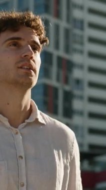 Güler yüzlü beyaz iş adamı şehre gidiyor binaların yakınına gökdelenler mutlu iş adamı gülümseyen işçi yatırımcı modern bölge yürüyüşüne bakıyor şehir merkezine gidiyor