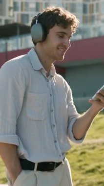 Aktif neşeli Kafkas iş adamı kulaklık takıyor cep telefonuyla müzik dinliyor şehir iş adamı erkek uzman dans uzmanı kulaklıkla müzik dinliyor akıllı telefon müzik uygulaması ile